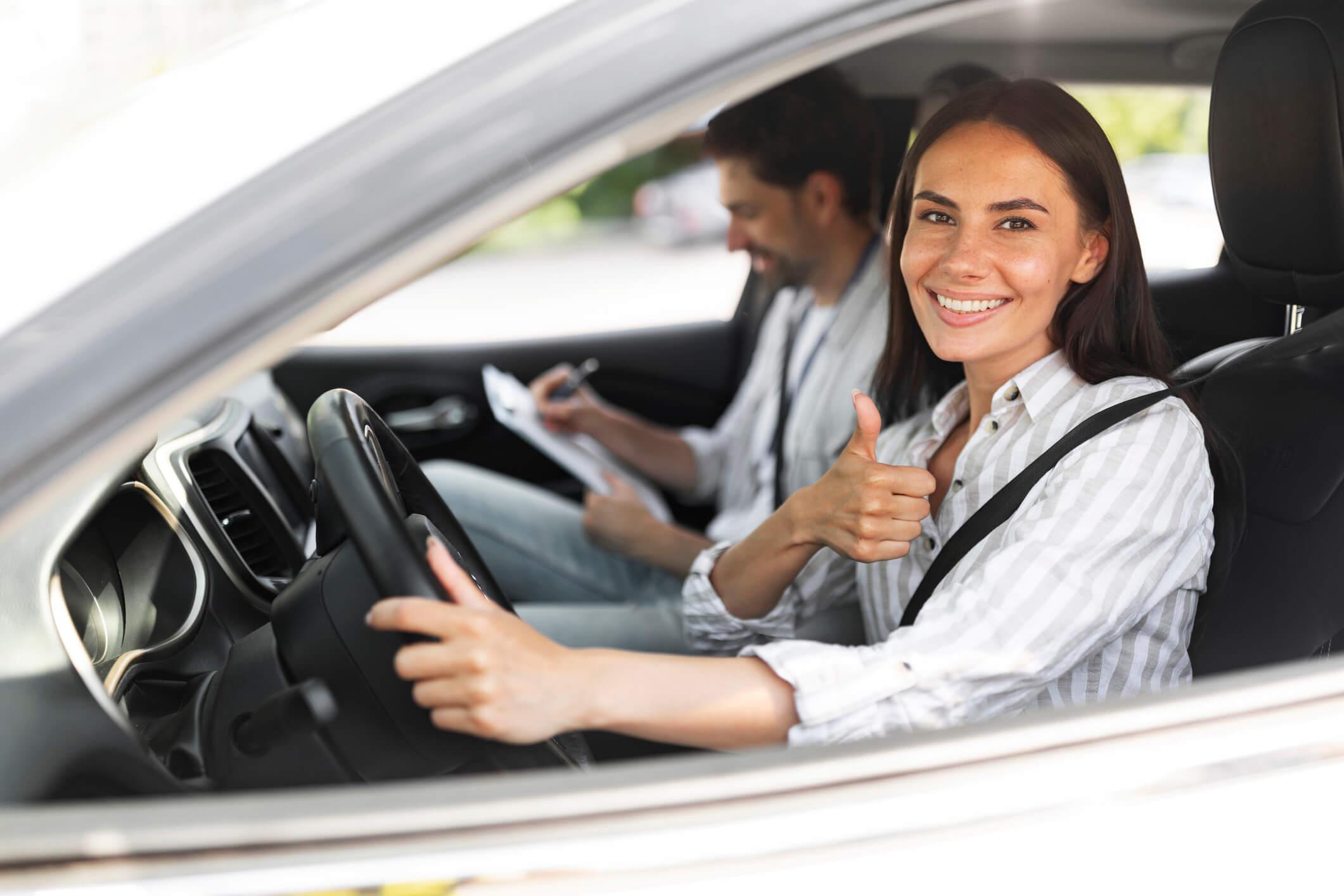 A girl smiling behind the wheel sitting with an instructor